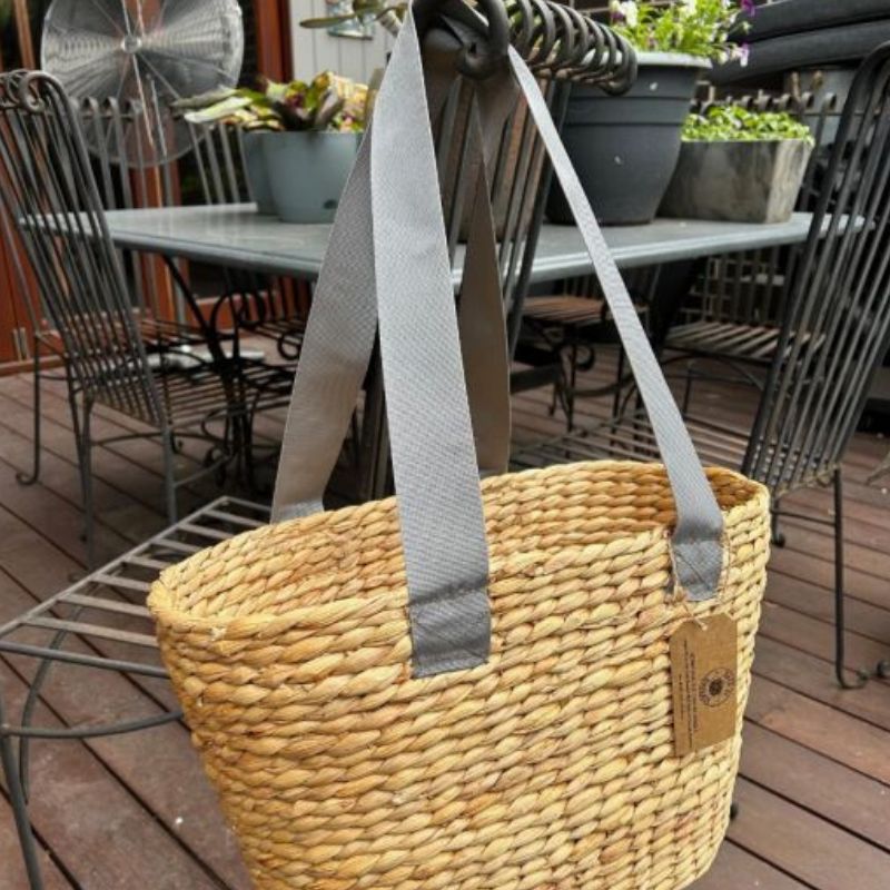 Back to Basket water hyacinth shoulder basket with green strap - hanging over chair.