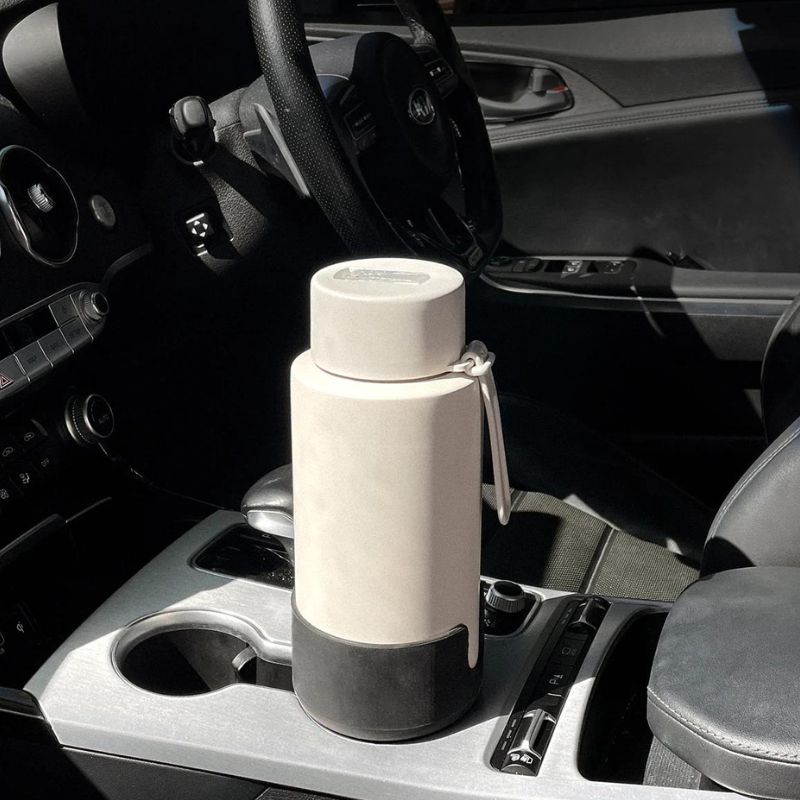 Frank Green car cup holder expander - in car with a bottle.