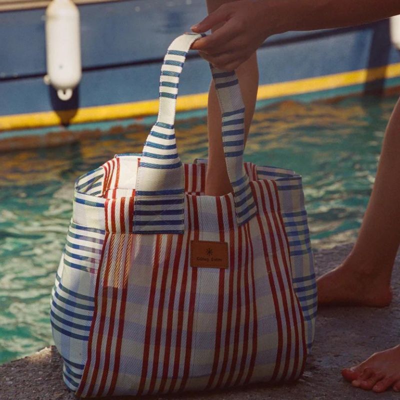 Gunes swim bundle tote beach bag in Chantilly Red - woman next to water holding it in her hand.
