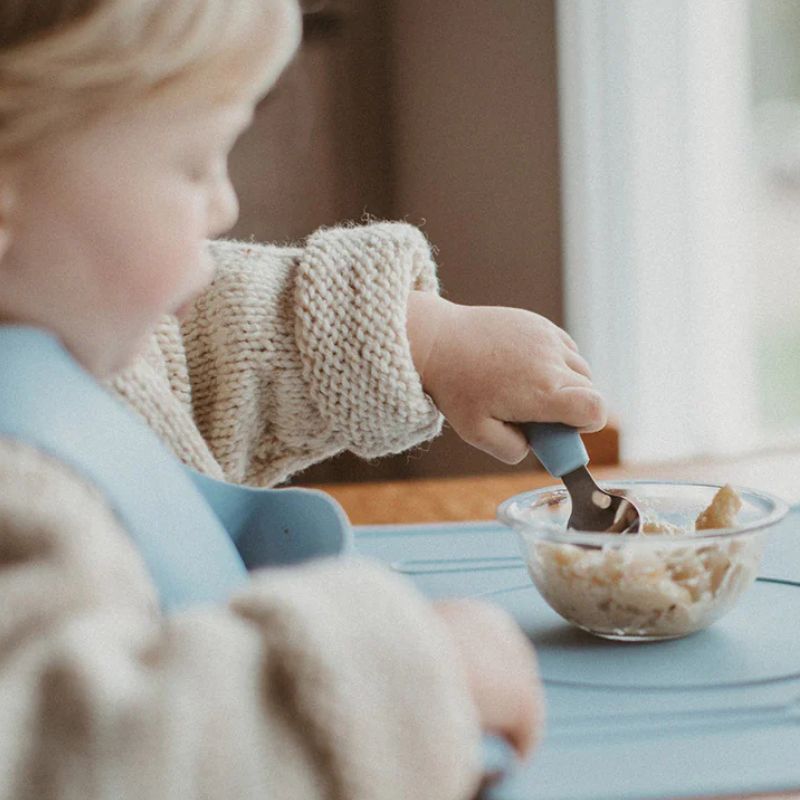 Montessori Mates soft grip toddler cutlery set - spoon, fork and knife - showing a child using the spoon.
