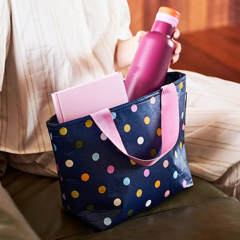 Project Ten mini tote  - photo showing a woman putting a bottle in a confetti bag. 
