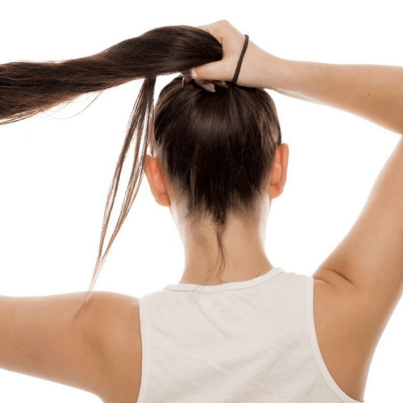 Green Essentials Natural Hair Ties no plastic, but natural rubber and organic cotton.  Woman putting her hair up in a pony tail.