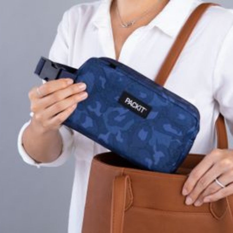 PackIt freezable snack box - woman putting one in the Heather Leopard Navy design in to her bag. 