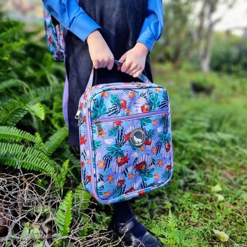 A child in the grass holding a Wolf Gang Arctic Wolf large insulated cooler lunch bag.